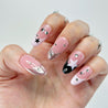 Hand with pink nails featuring star and arrow designs on a white background