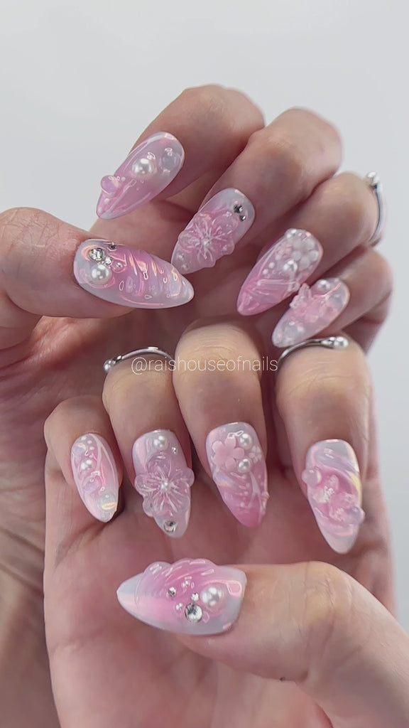 Video showing Rai's House of Nails pink jelly press on nails in motion, with iridescent shine, 3D flowers, butterflies, pearls, and rhinestones catching the light.