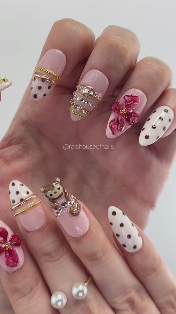 Video showing Rai's House of Nails 3D monkey and berry flower press on nails in motion, with glossy flowers, polka dots, and gold details catching the light.