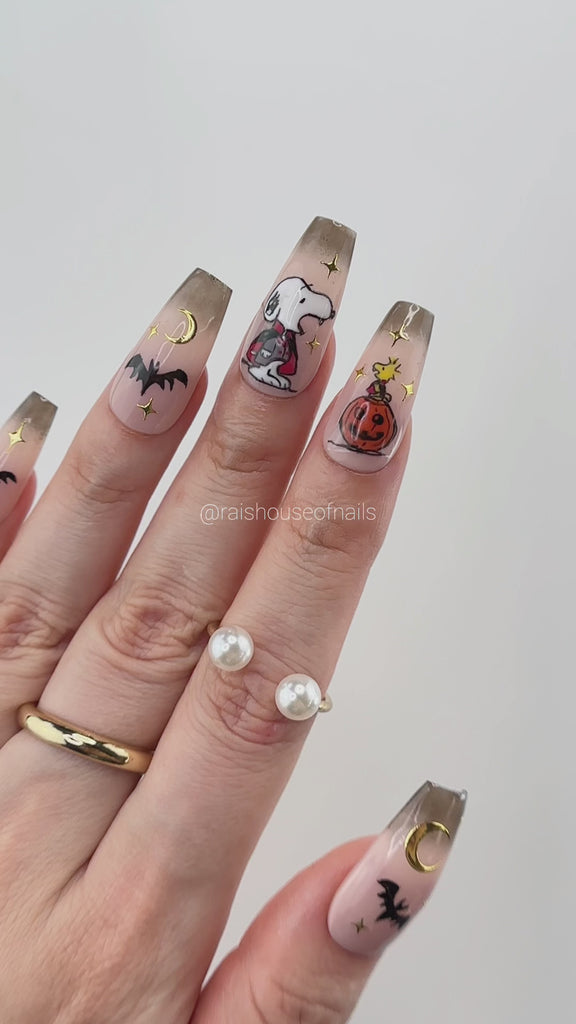 Video showing Rai's House of Nails Halloween cartoon dog press on nails in motion, with the hand painted characters, gold charms, and ombre tips catching the light.