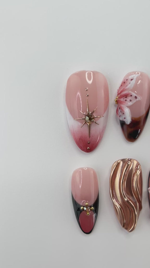 Video showing Rai's House of Nails tortoiseshell lily press on nails in motion, with the chrome swirl, gold stars, and floral details catching the light.